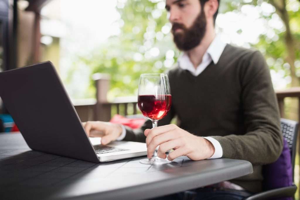 Man using laptop while having glass of wine in bar
